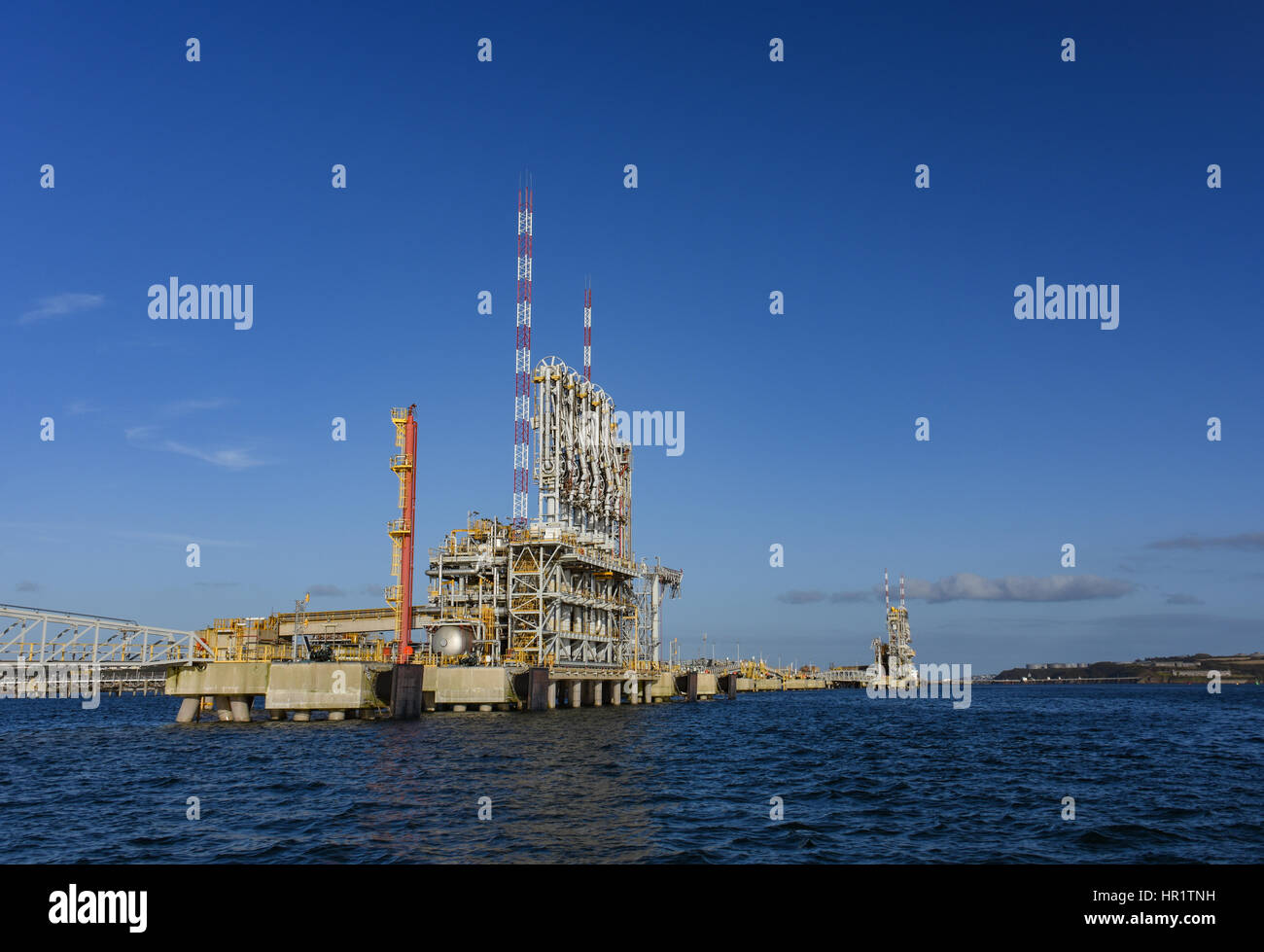 Scarica di gas di apparecchiature a sud il gancio terminale GNL in posizione di riposo contro un cielo azzurro con poche nuvole wispy Foto Stock