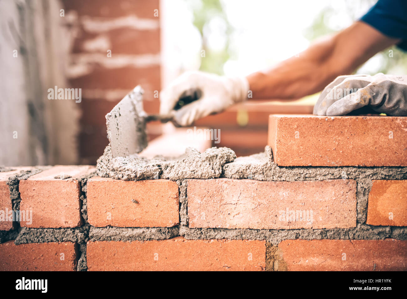 Muratore lavoratore installazione di muratura di mattoni sulla parete esterna con cazzuola spatola Foto Stock