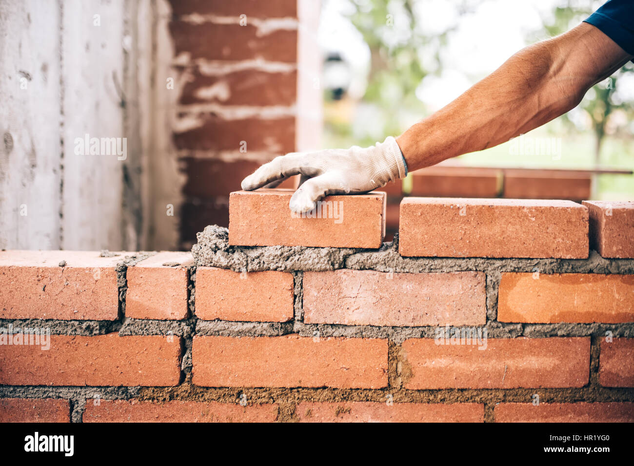 Muratore industriale lavoratore immissione mattoni sul cemento mentre la costruzione di muri esterni, industry Dettagli Foto Stock