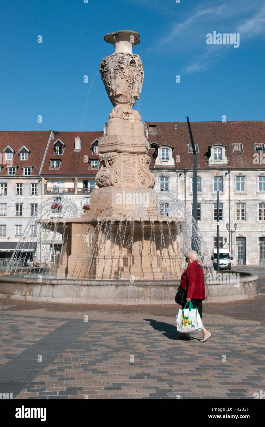Donna con rivestimento rosso passeggiate passato fontana monumento in Place de la rivoluzione Besancon Francia Foto Stock