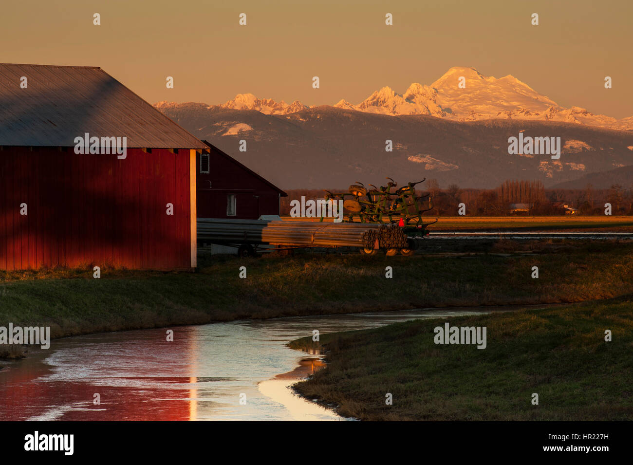 La luce del tramonto rosso con fienile e campi e il Monte Baker Foto Stock