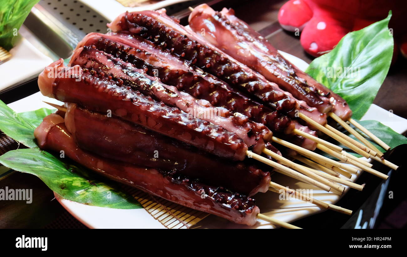 Cucina asiatica di materie octopus tentacoli su stick preparato per la cottura o per il barbeque Foto Stock