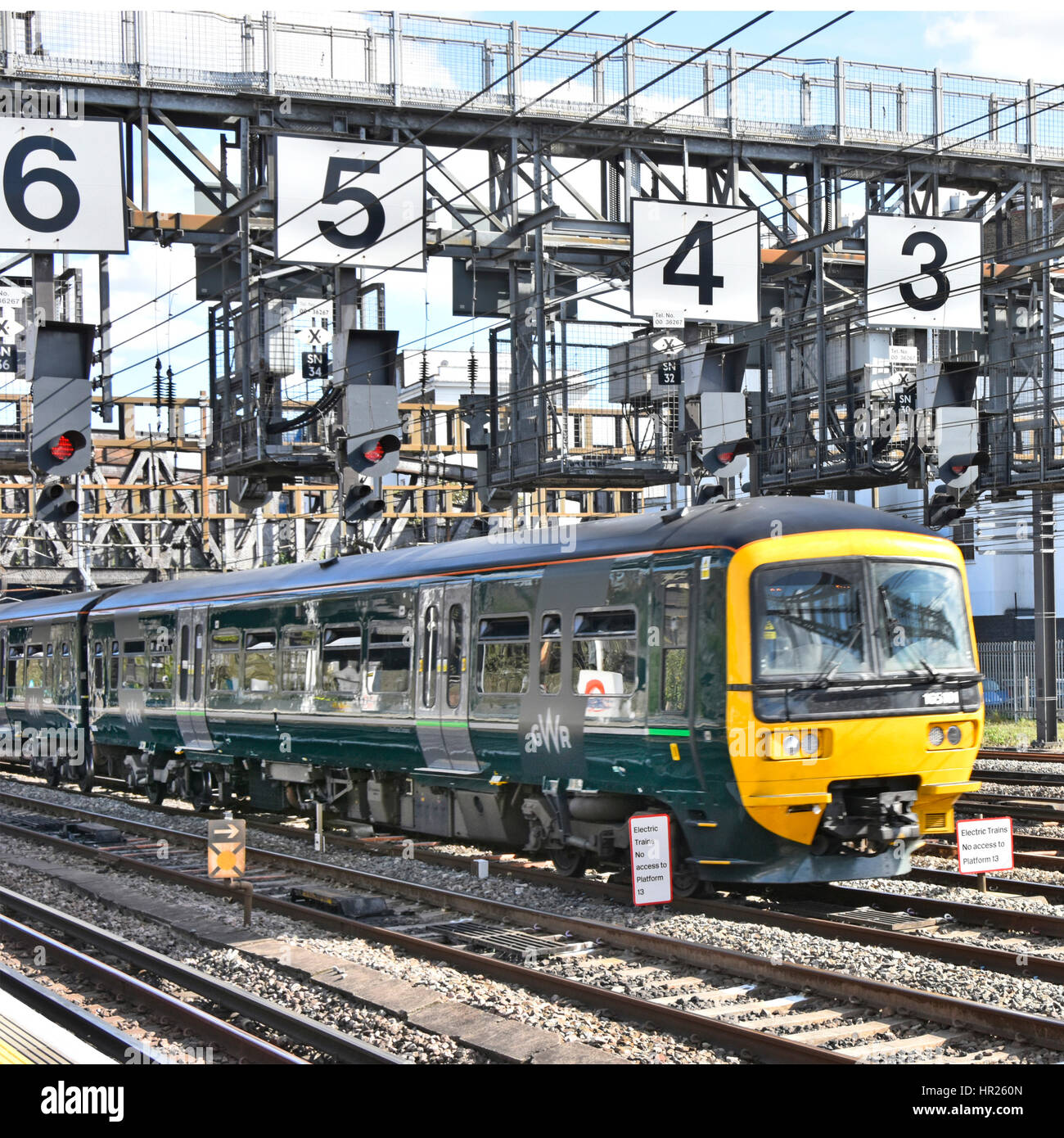 Segnalazione ferroviaria Regno Unito di binari ferroviari GWR treno su binari appena fuori la stazione Paddington di Londra passando sotto il segnale del gantry numeri di grandi dimensioni Foto Stock