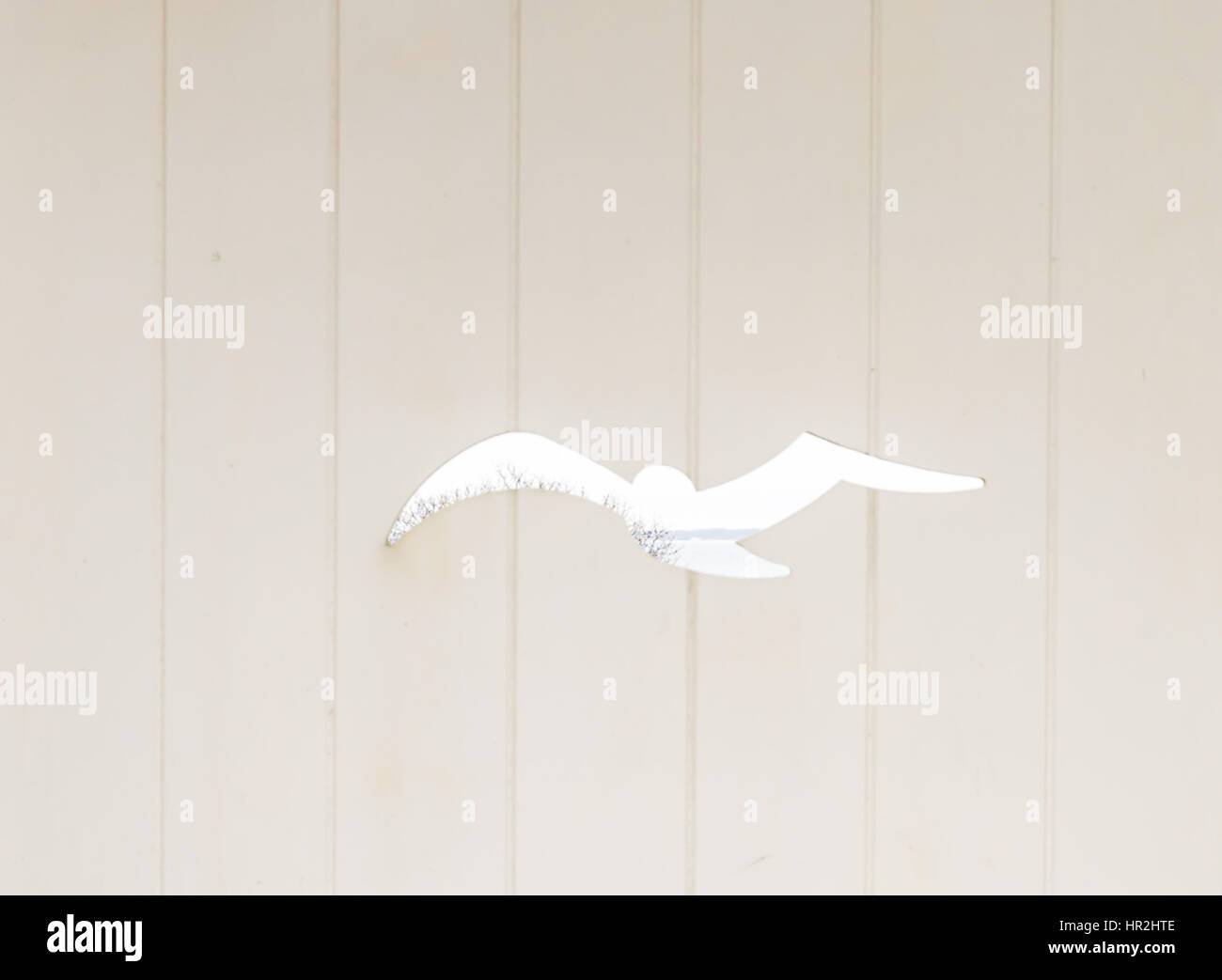 Uno spaccato di un uccello in volo in una porta di legno Foto Stock