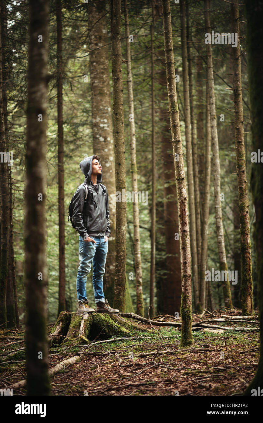 Incappucciati giovane uomo in piedi nella foresta ed esplorare, la libertà e il concetto di natura Foto Stock