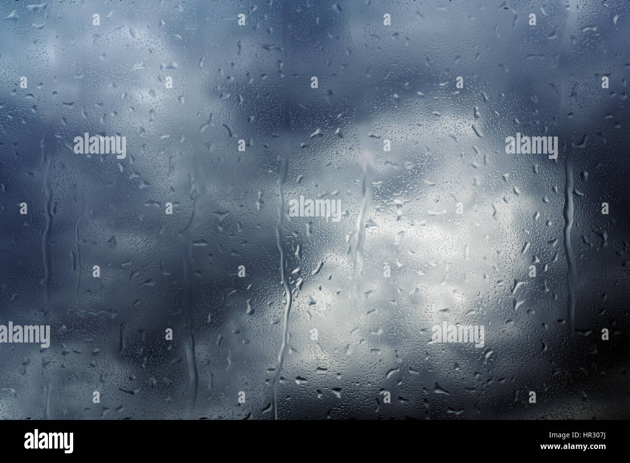 Le gocce di pioggia proveniente da molto nuvole scure su una finestra Foto Stock