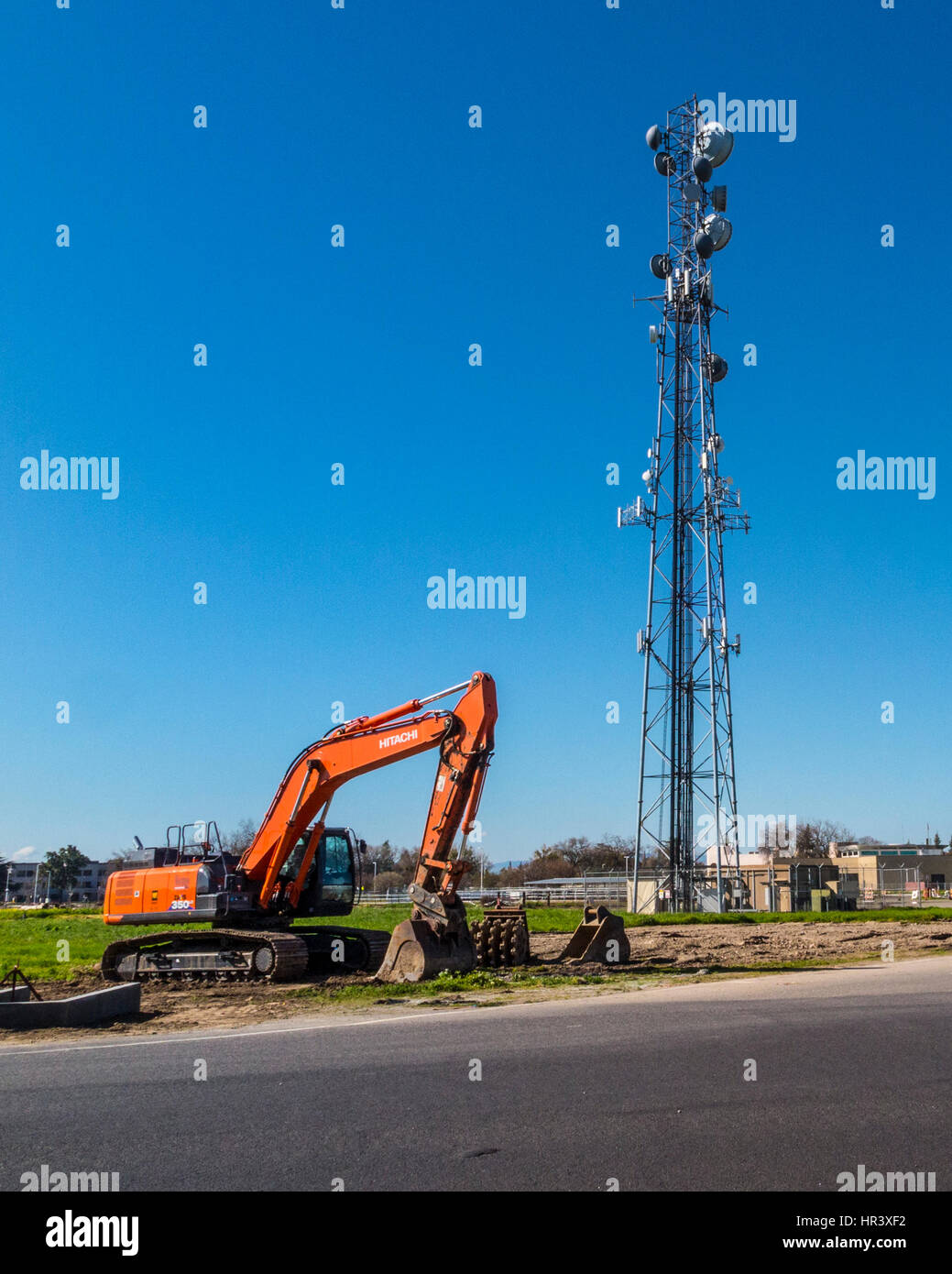 Un escavatore esegue il lavoro a una torre mobile site sul campus di Modesto Junior College Foto Stock