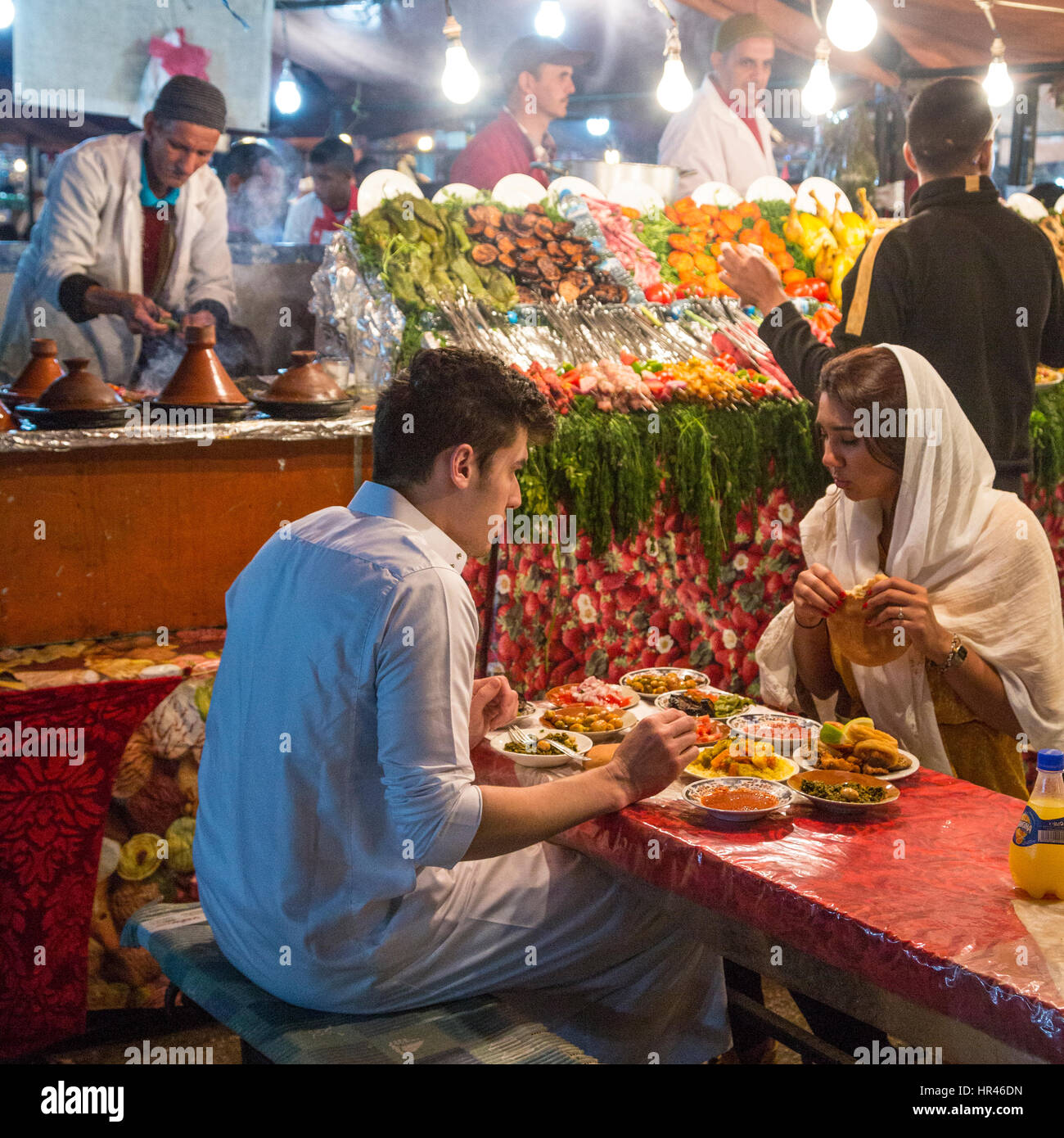 Marrakech, Marocco. Coppia giovane mangiare al cibo in stallo, Place Jemaa El-Fná. Foto Stock