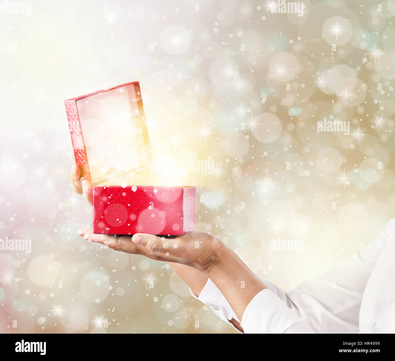 Mani e pening una confezione regalo rossa con magici effetti speciali luci. Foto Stock