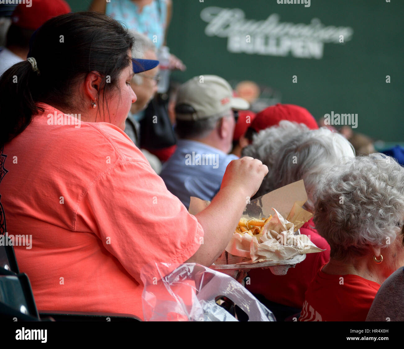 Donna sovrappeso a mangiare cibo ad una partita di baseball Foto Stock