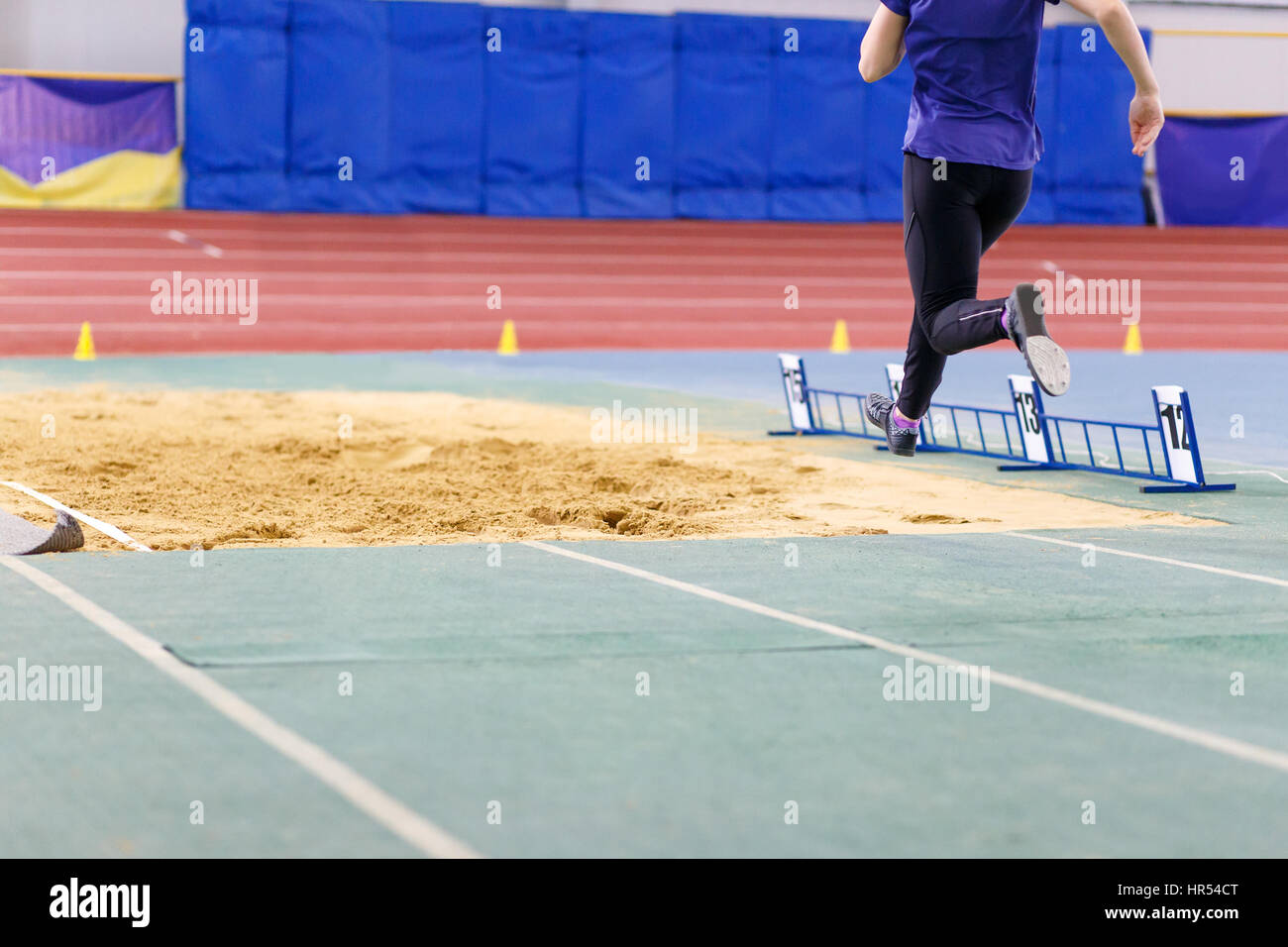 Sportive un salto nella buca di sabbia sul salto triplo concorrenza in pista e sul campo campionato Foto Stock