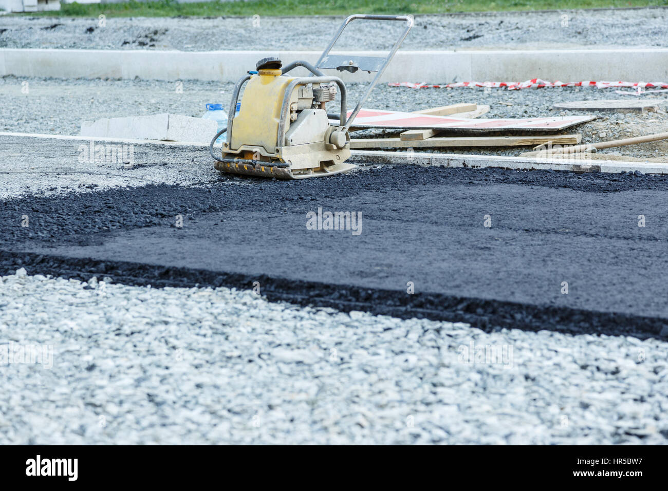 La piastra vibrante compattatore di asfalto di compattazione a riparazione su strada Foto Stock