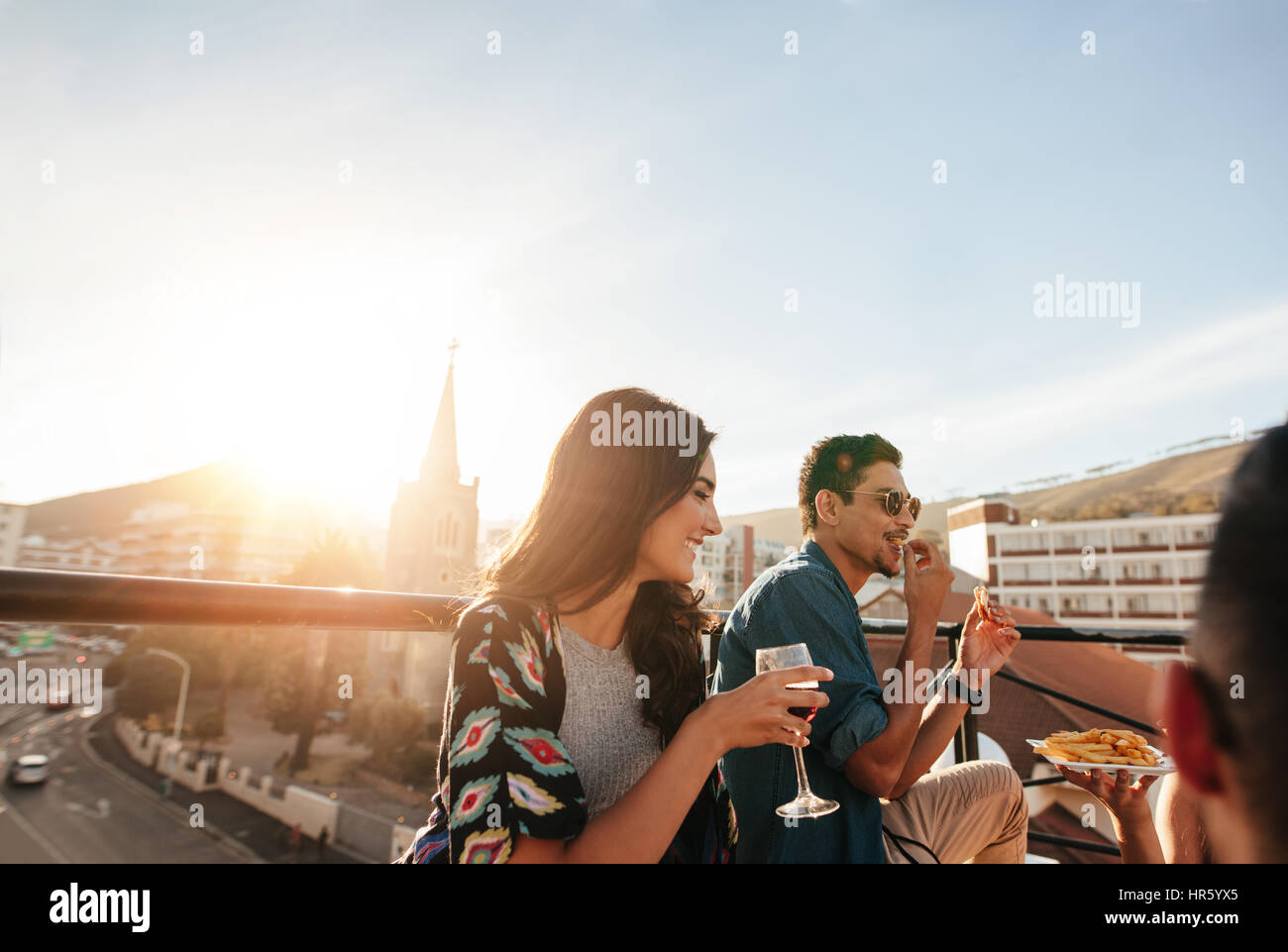 Giovane donna avente un drink con gli amici. Gruppo di amici partying sul tetto. Foto Stock Giovane donna avente un drink con gli amici. Gruppo di amici partying sul tetto. Foto Stock