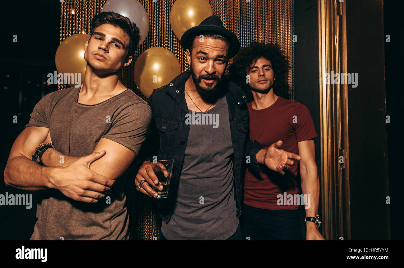 Ritratto di tre giovani uomini in piedi in un night club. Elegante gruppo di uomini al pub. Foto Stock
