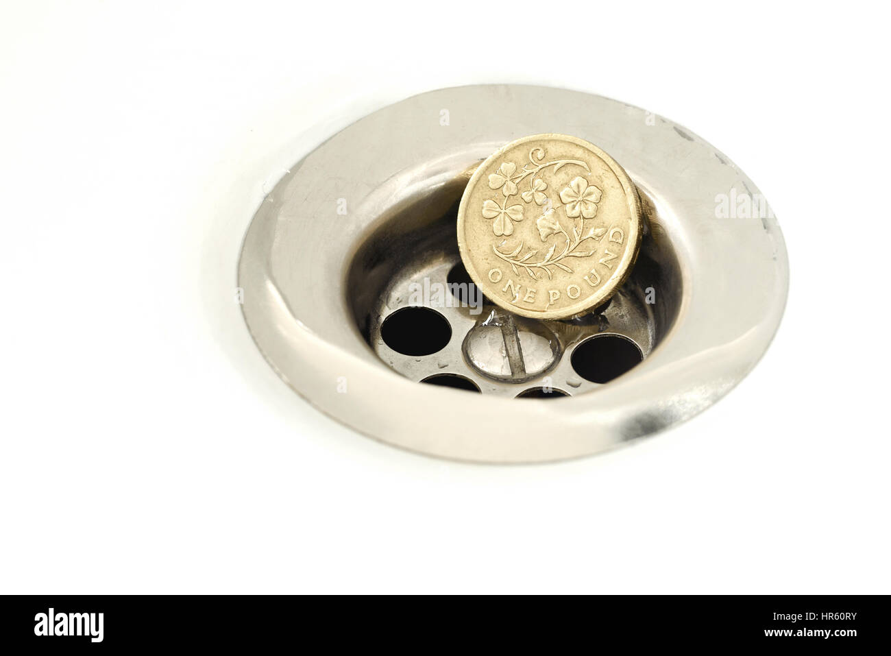 Unico British Pound Coin di riposo in argento scarico con goccioline di acqua sulla moneta e bianco superficie ceramica Foto Stock