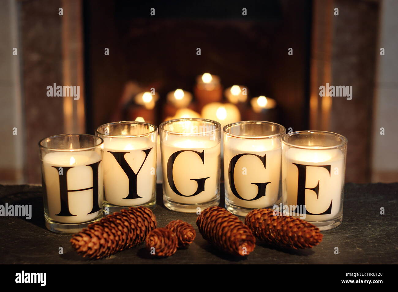 Fireside candele in un inglese home inverno raffigurano "hygge' - il concetto danese di abbracciando accoglienti appagamento e convivialità Foto Stock