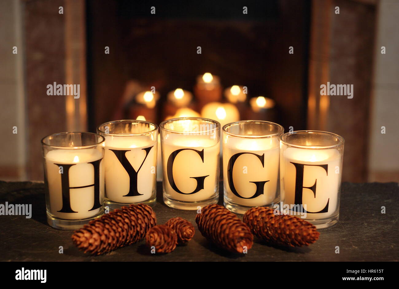 Fireside candele in un inglese home inverno raffigurano "hygge' - il concetto danese di abbracciando accoglienti appagamento e convivialità Foto Stock