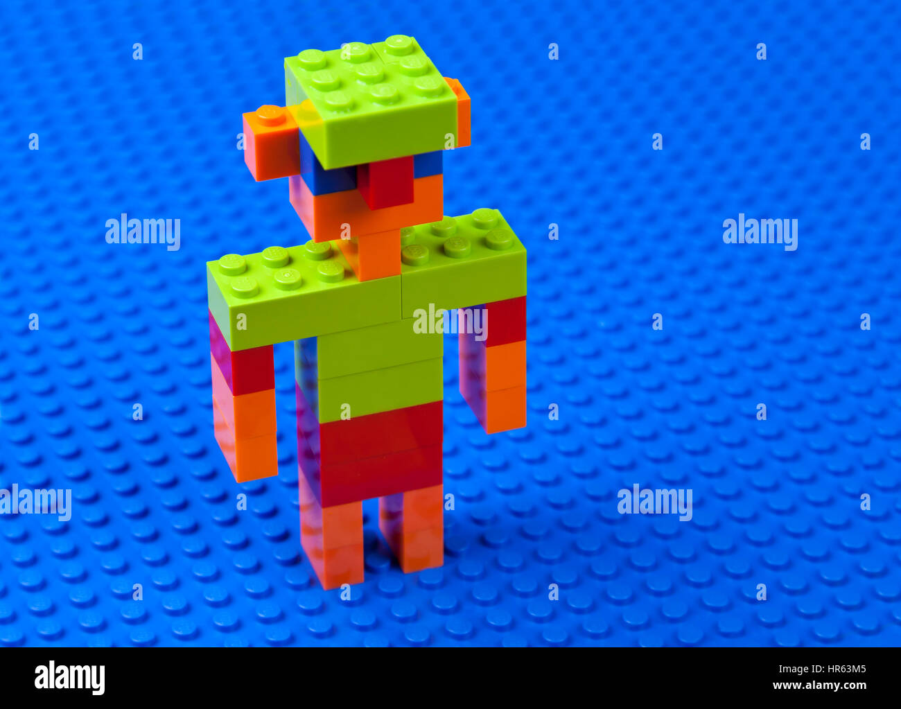 L'uomo, boy, maschio con caraffa-orecchie e un cappuccio verde costruito di mattoncini Lego su un blu Lego piastra di base - dedicarmi o guadare in acqua blu Foto Stock