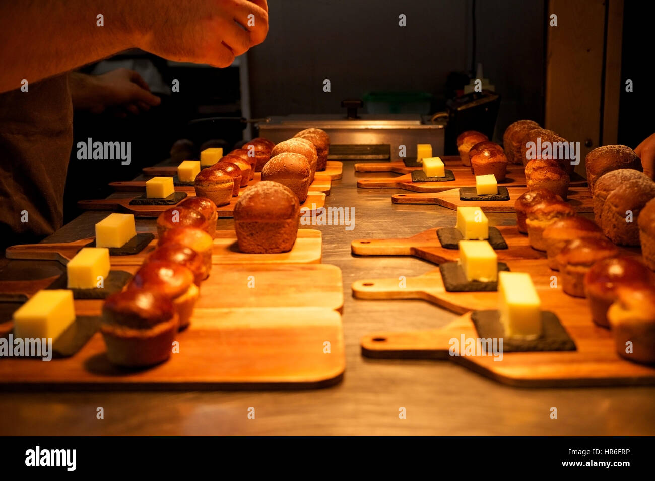 I piccoli rotoli di pane fatto in casa e le piazze di burro su assi di legno posati su silver top da cucina pronti per essere serviti in un ristorante, gli chef ha Foto Stock