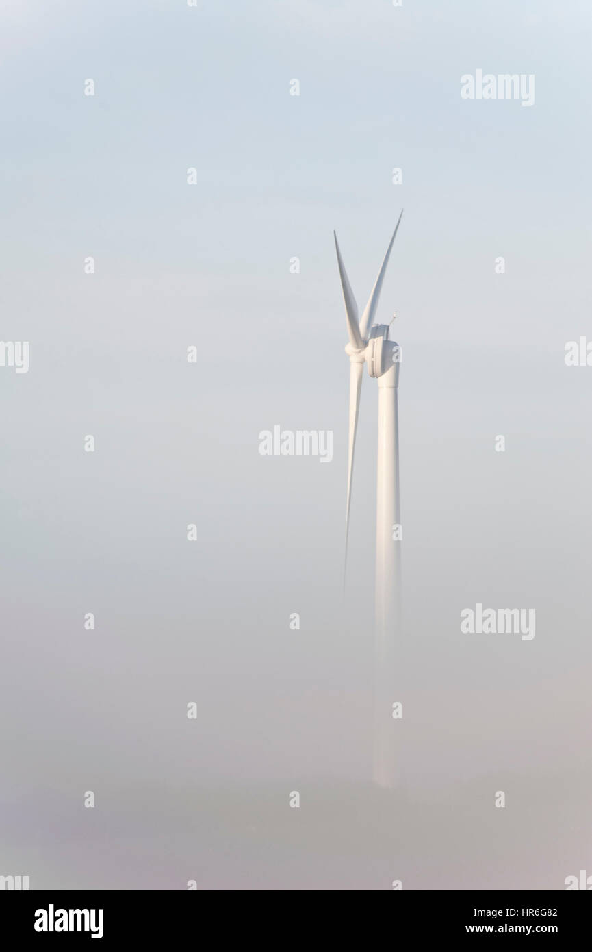 Orientamento verticale, turbine eoliche passando da un banco di nebbia Foto Stock