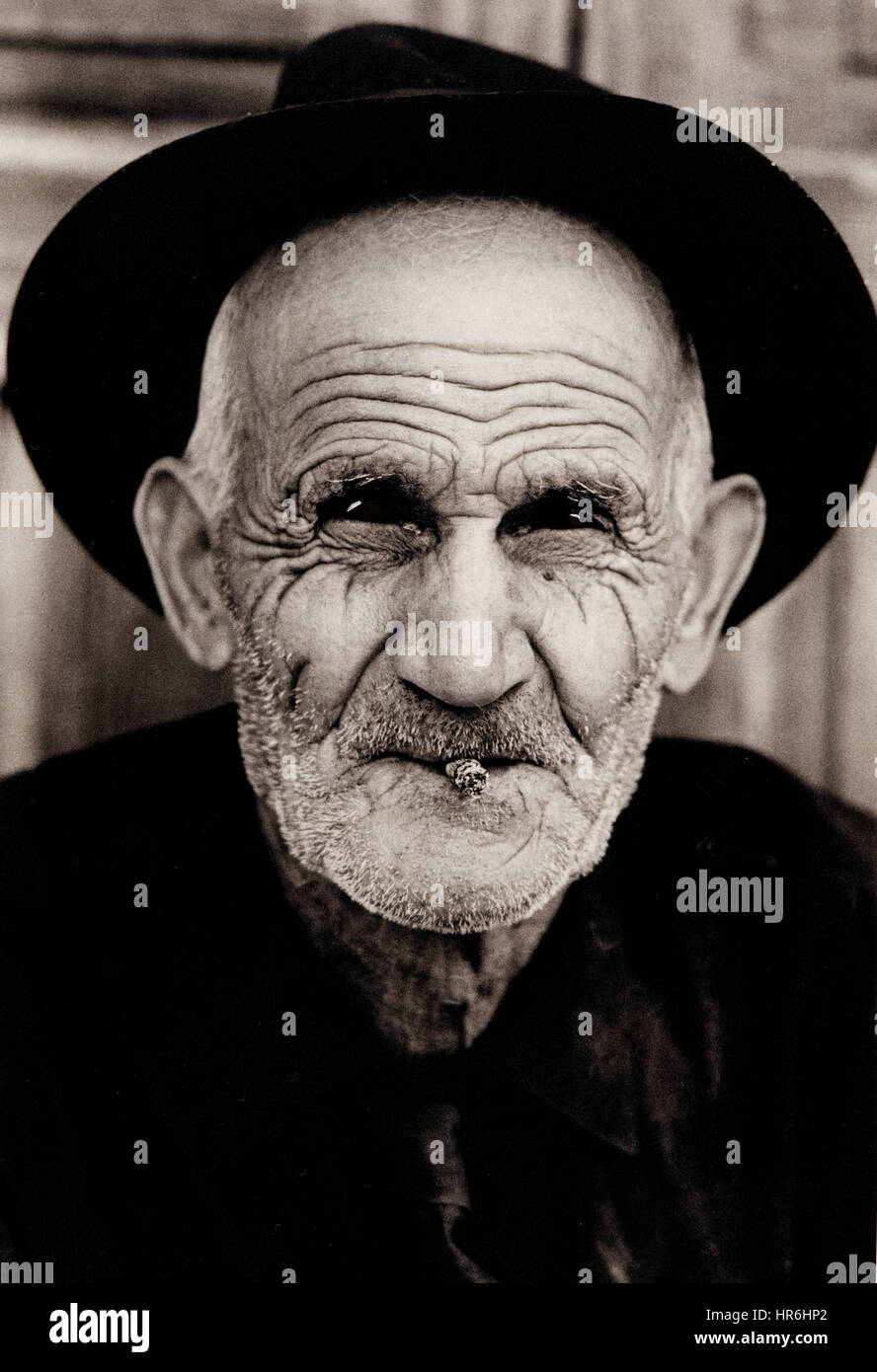 VECCHIO PERSONAGGIO FODERATO B+W ritratto foderato sole tempo battuto volto studio di anziano gentleman con sigarillo indossare un cappello a Vegueta, Las Palmas, Isole Canarie Spagna Foto Stock