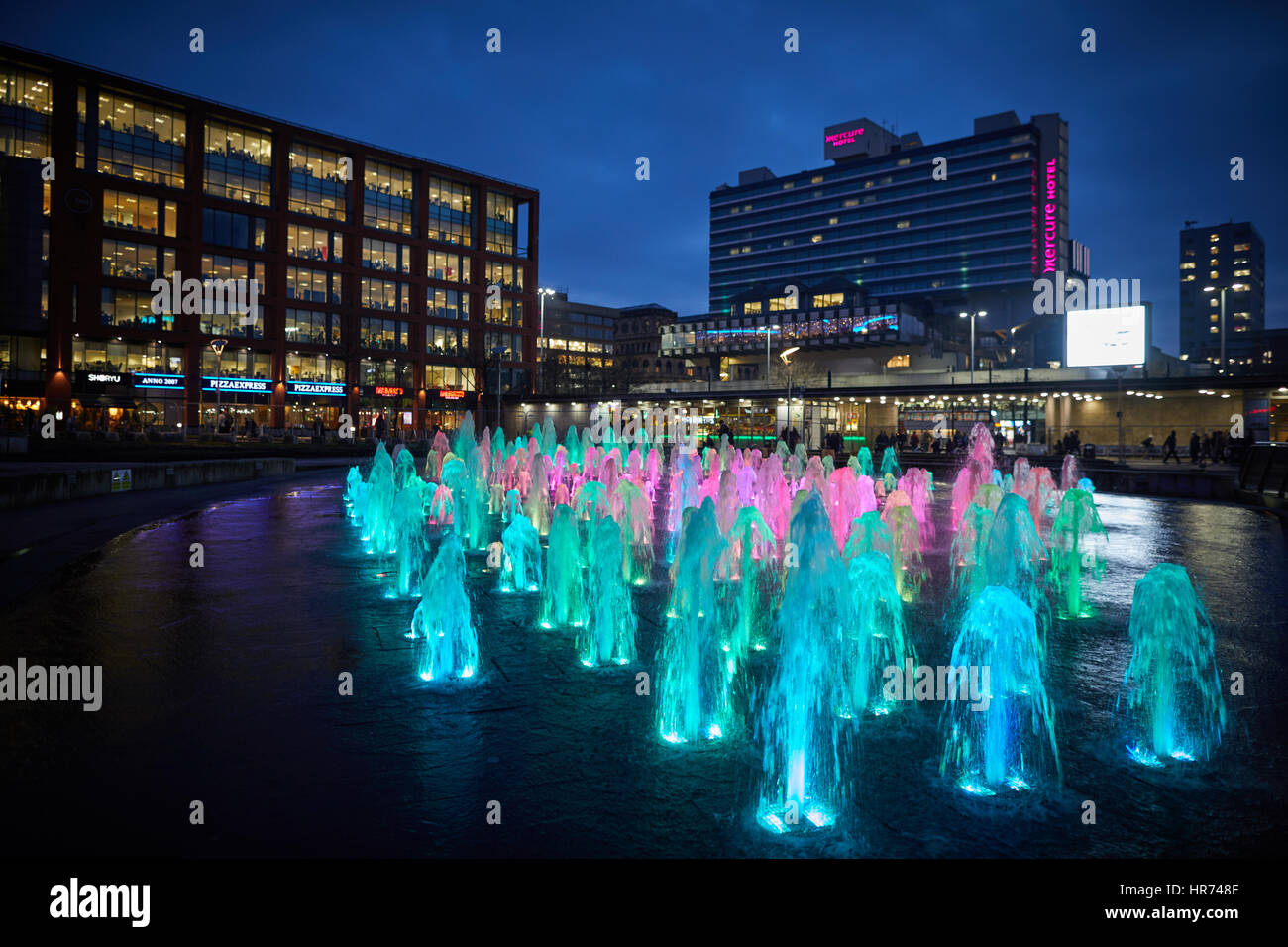Il centro città di Manchester Piccadilly Gardens landmark fontana di acqua il display si illumina di notte. Foto Stock