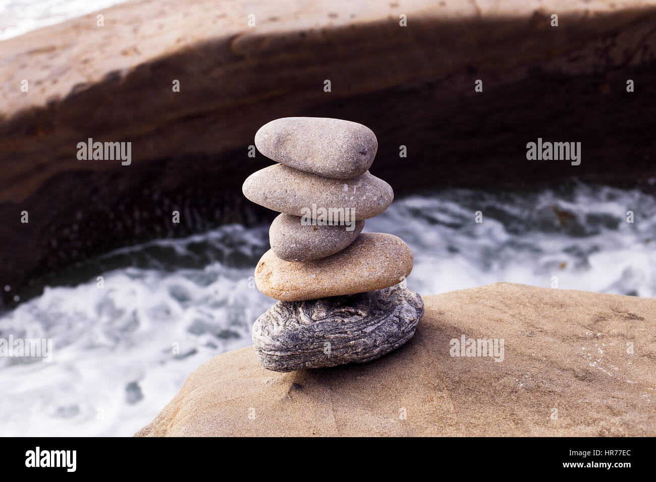 Una pila di rocce bilanciate con acqua sullo sfondo Foto Stock