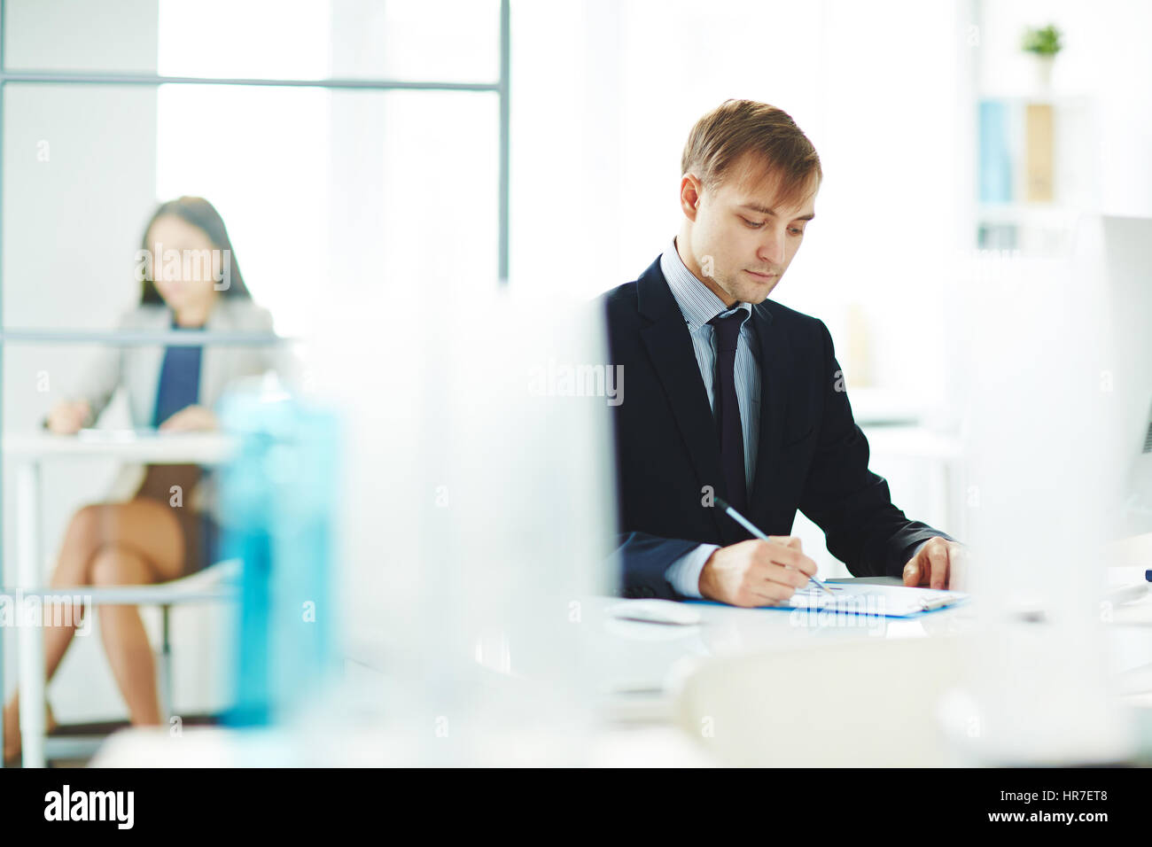 Ritratto di giovane business analyst controllo report statistiche con grafici stando seduti al posto di lavoro in un moderno ufficio di luce Foto Stock