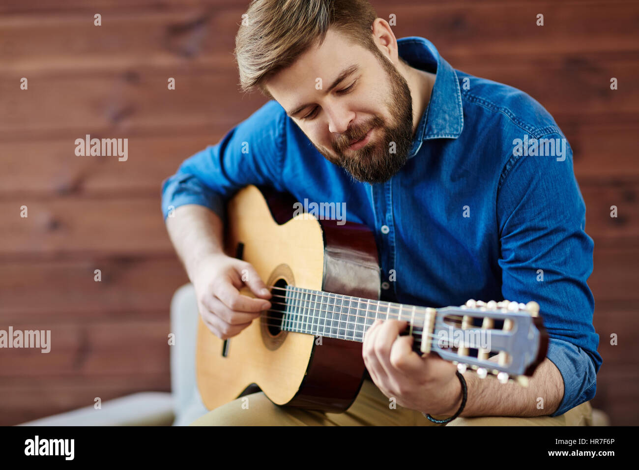 Processo di creazione musicale: sorridente giovane uomo in denim shirt avvolto nella composizione di nuova melodia Foto Stock