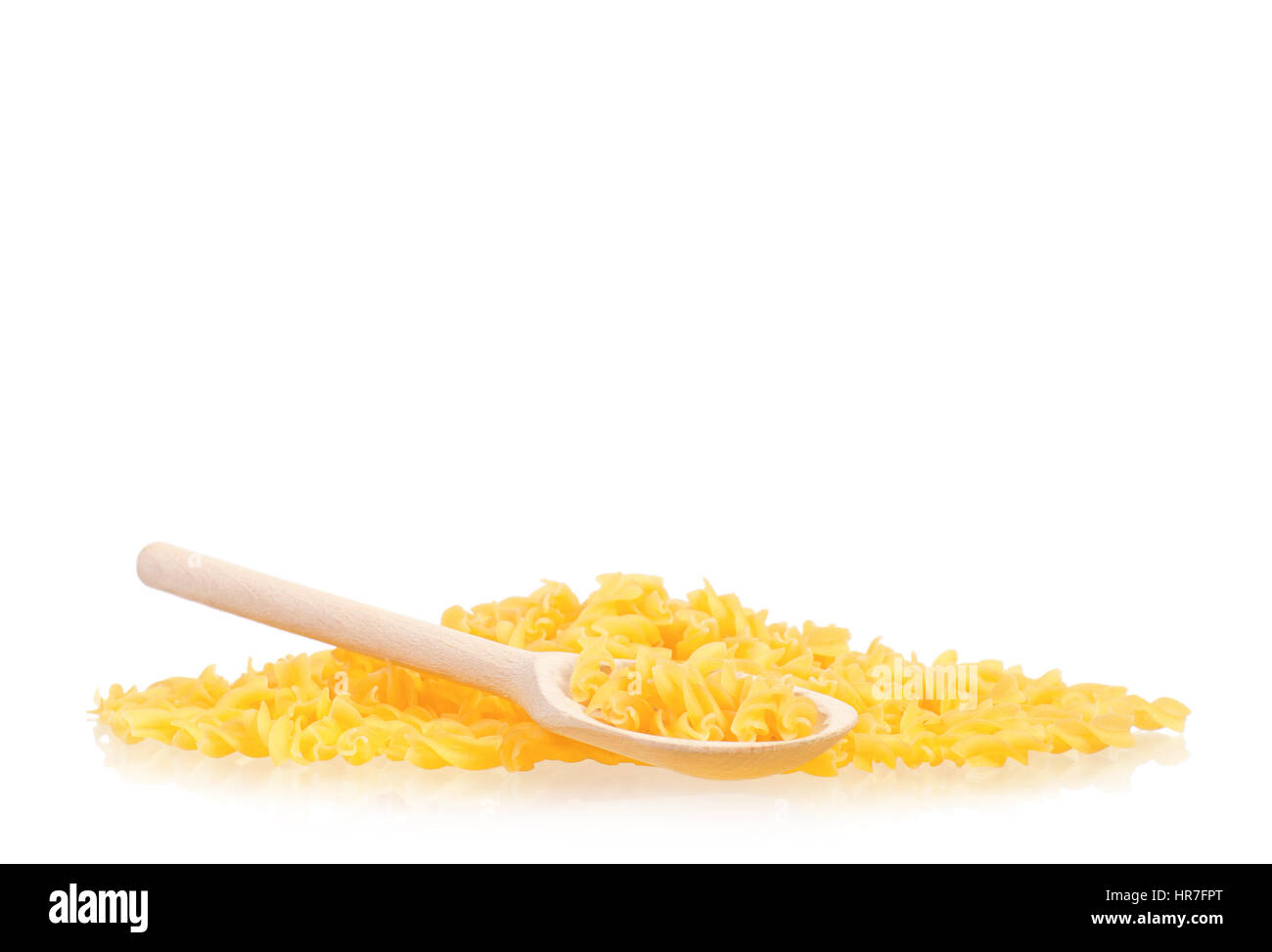 Cucchiaio di legno secco con pasta di colore giallo isolato su sfondo bianco. Non cotti Italian pasta penne. Foto Stock