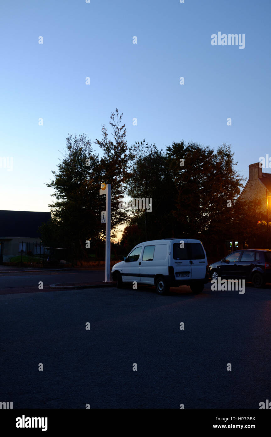 Bianco auto in un parcheggio di campagna durante le ore blu del tramonto in Normandia, Francia Foto Stock