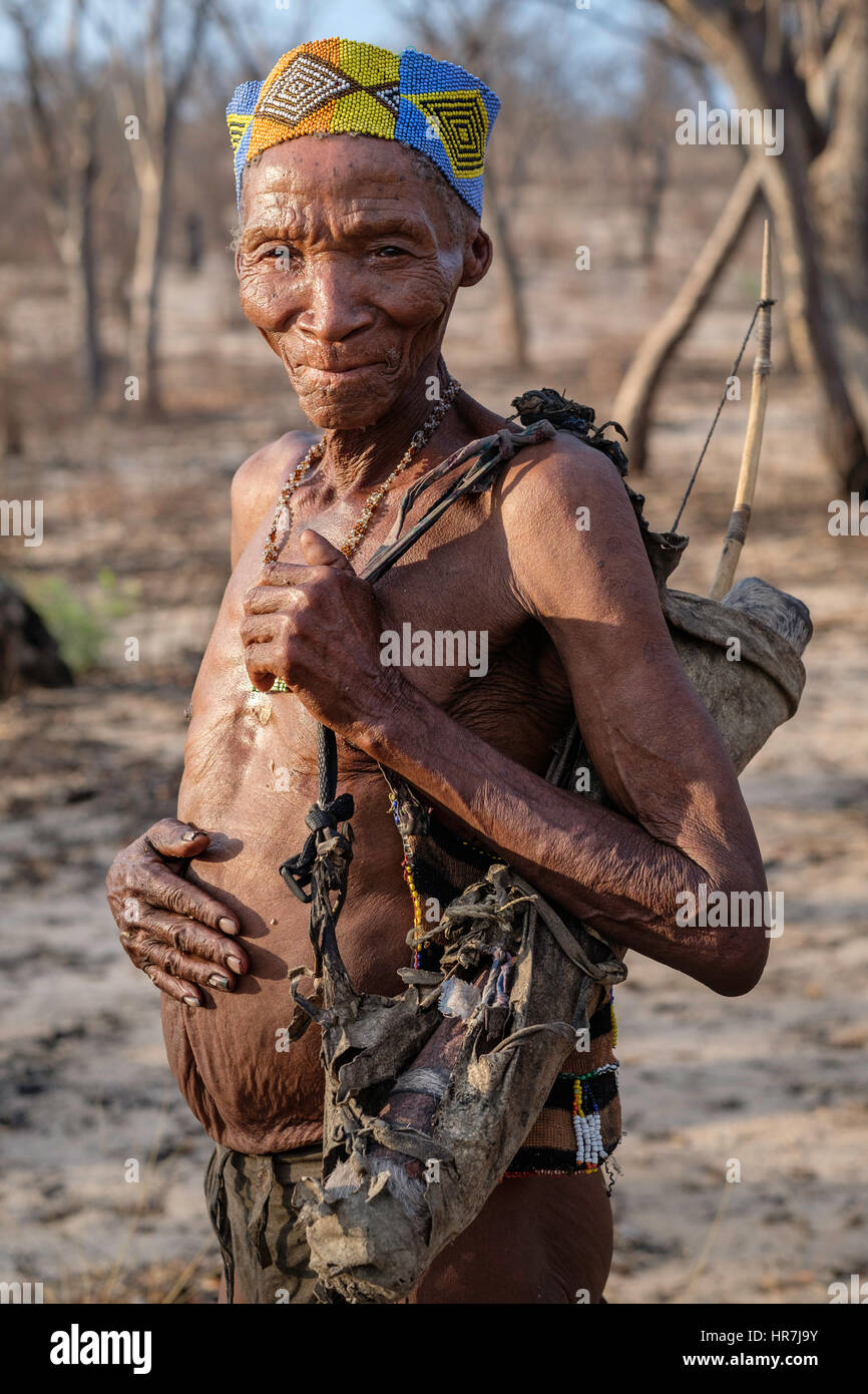 Ritratto di un uomo vecchio dal San tribù a piedi nel bush con le tradizionali armi e vestiti. San persone non hanno molte possibilità di mantenere con thei Foto Stock