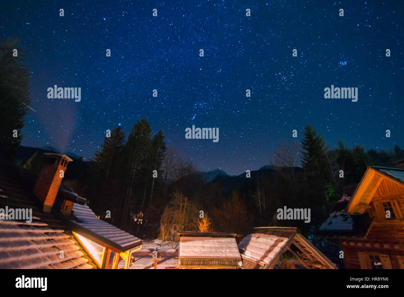 Cielo notturno e stelle sopra cabine in montagna in inverno, idilliaco scena di mezzanotte Foto Stock