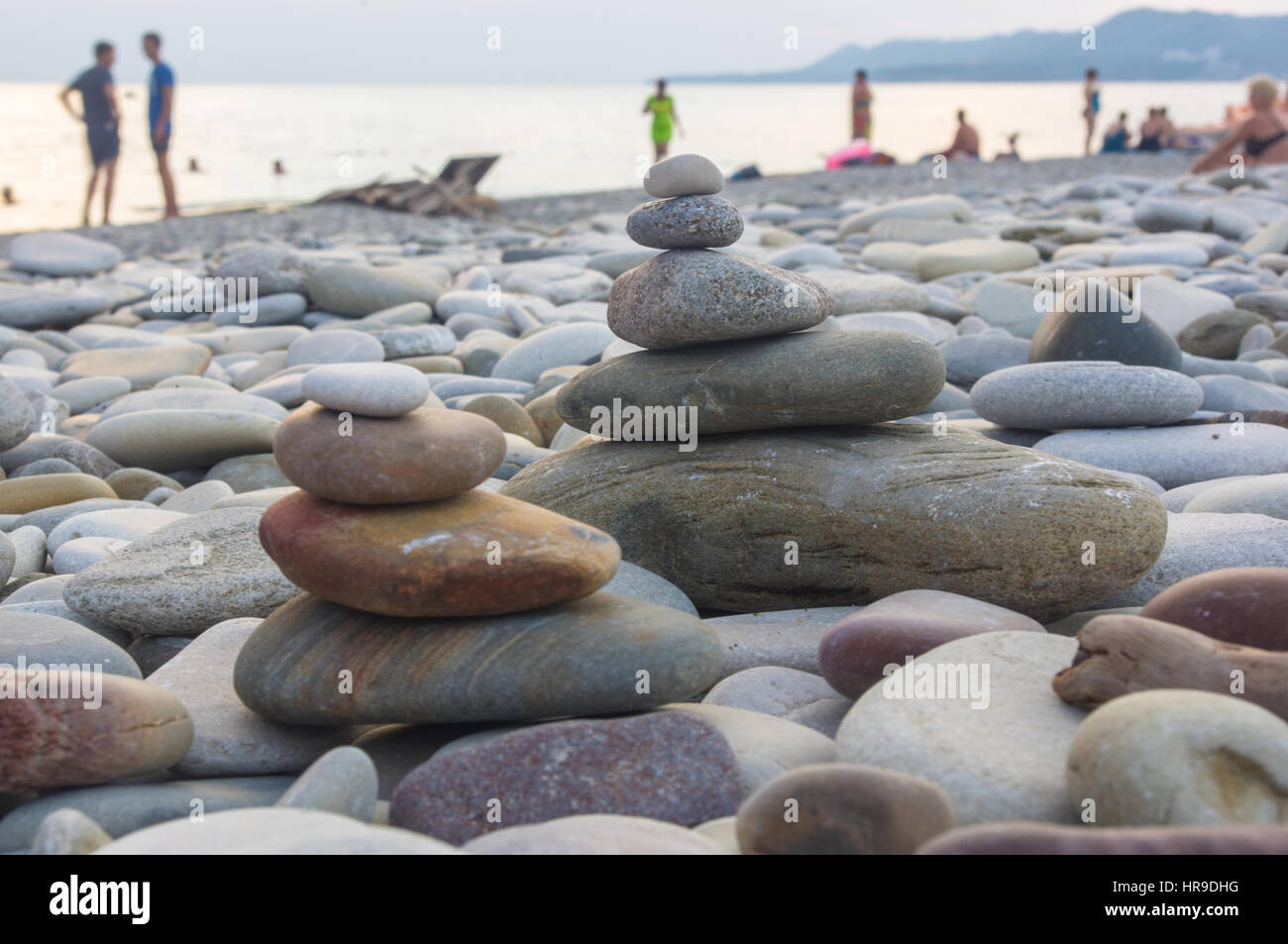Piramide piegata Zen pietre ghiaia sul mare spiaggia al tramonto Foto Stock