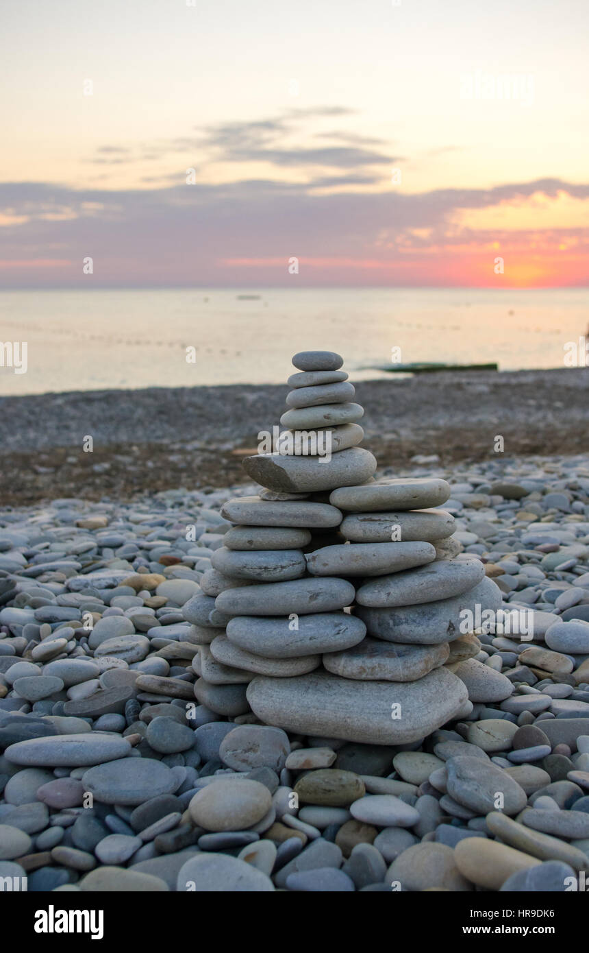 Piramide piegata Zen pietre ghiaia sul mare spiaggia al tramonto Foto Stock