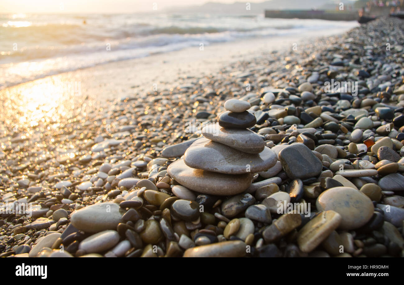 Piramide piegata Zen pietre ghiaia sul mare spiaggia al tramonto Foto Stock