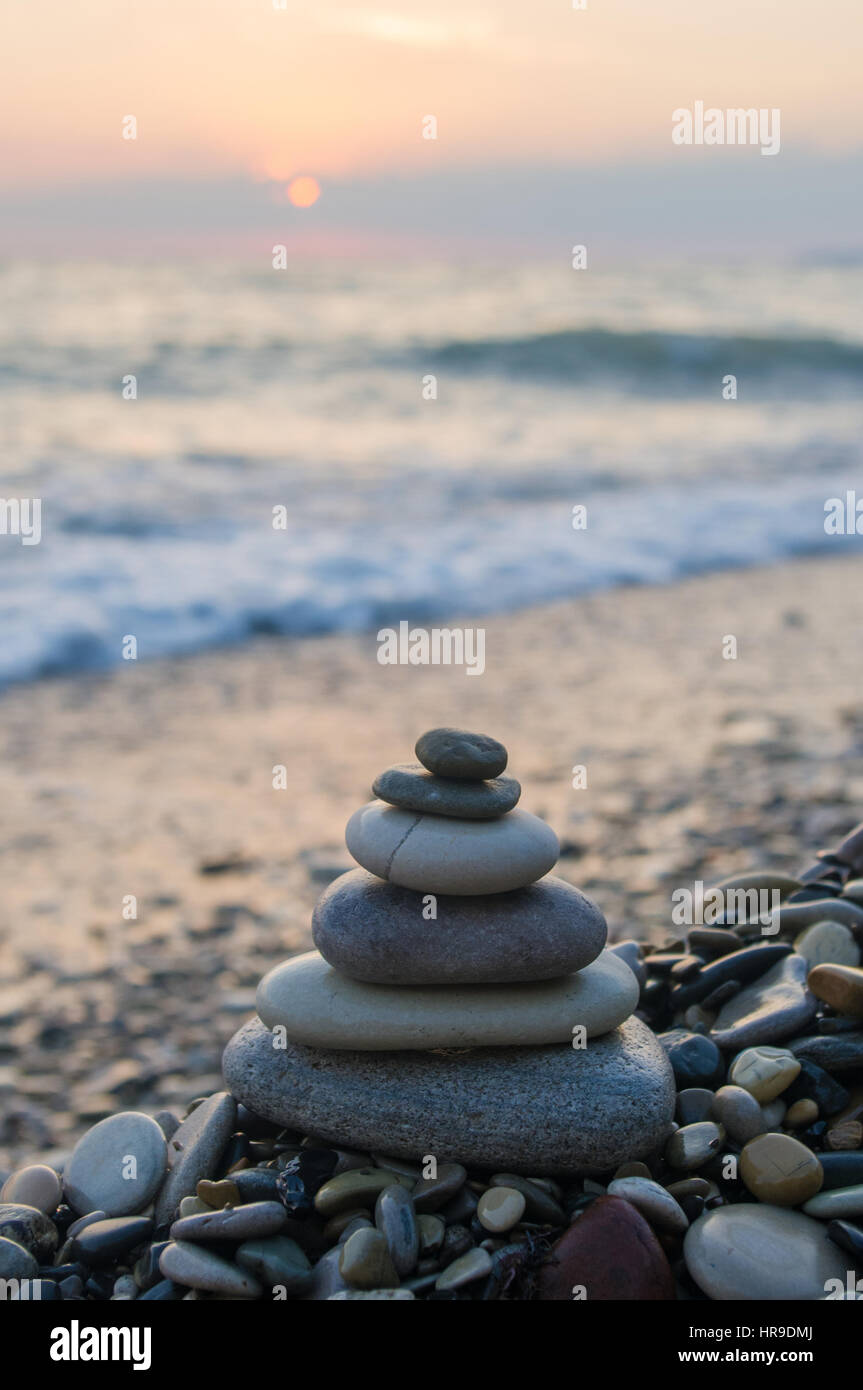 Piramide piegata Zen pietre ghiaia sul mare spiaggia al tramonto Foto Stock