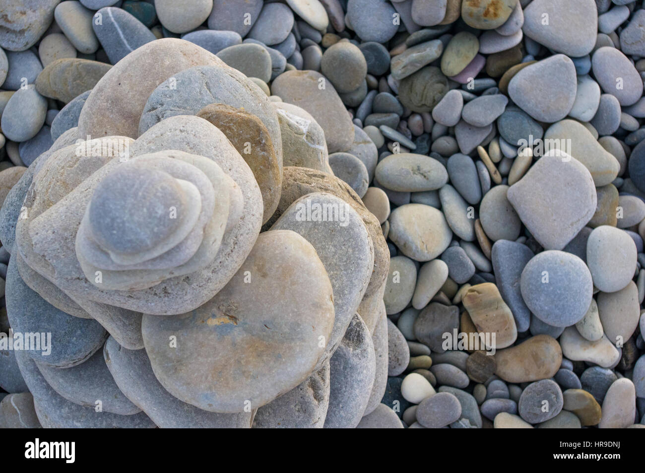 Piramide piegata Zen pietre ghiaia sul mare spiaggia al tramonto Foto Stock