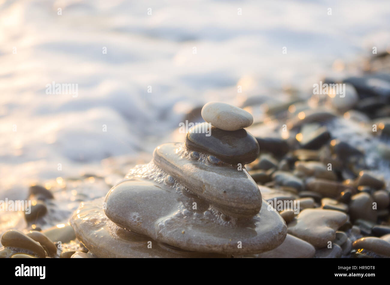 Piramide piegata Zen pietre ghiaia sul mare spiaggia al tramonto Foto Stock