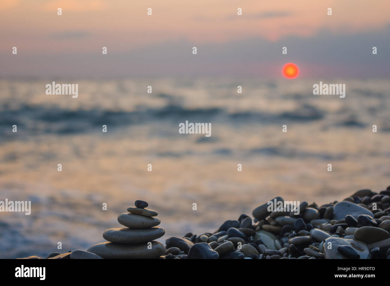 Piramide piegata Zen pietre ghiaia sul mare spiaggia al tramonto Foto Stock