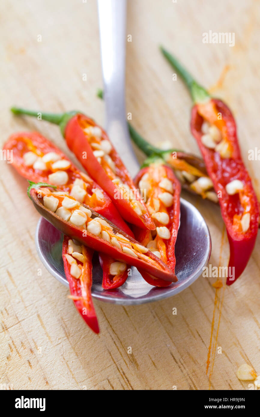 Red hot e peperoncino piccante peperoni, piccolo hot-pod di degustazione di una varietà di capsicum, le fette su un cucchiaio da tavola. È utilizzato in salsa, condimenti e spezie in polvere Foto Stock
