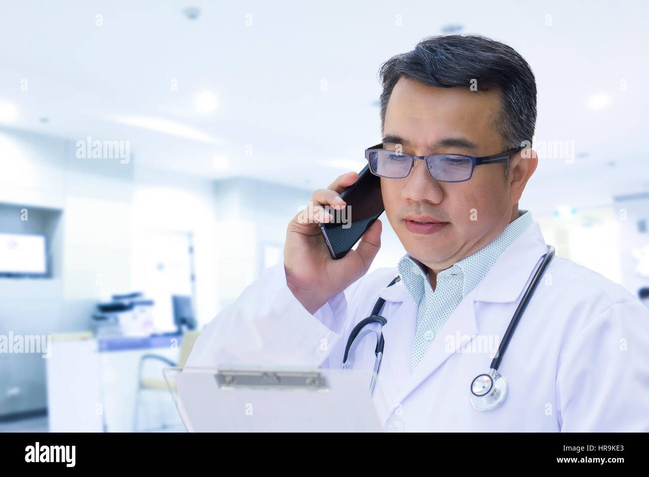 Medico utilizzando il telefono cellulare e guardando il record del paziente in alto tono tasto Foto Stock