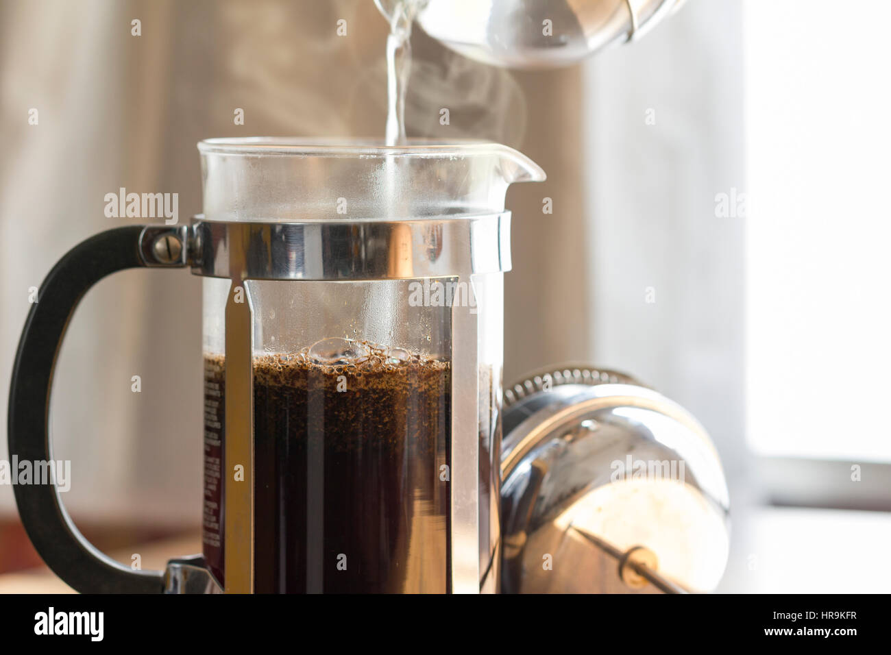 Per l'infusione di caffè in una pressa francese nella calda luce del mattino che mostra la preparazione della bevanda di caffè. Si tratta di un studio shot con copia spazio sulla destra. Foto Stock