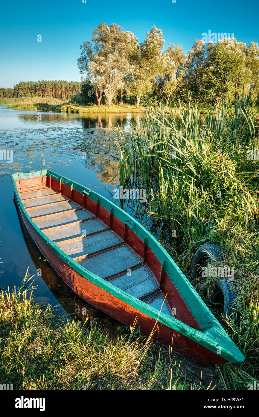 Lago o fiume e vecchio blu in legno a remi in barca da pesca in estate  bella giornata di sole o la sera Foto stock - Alamy