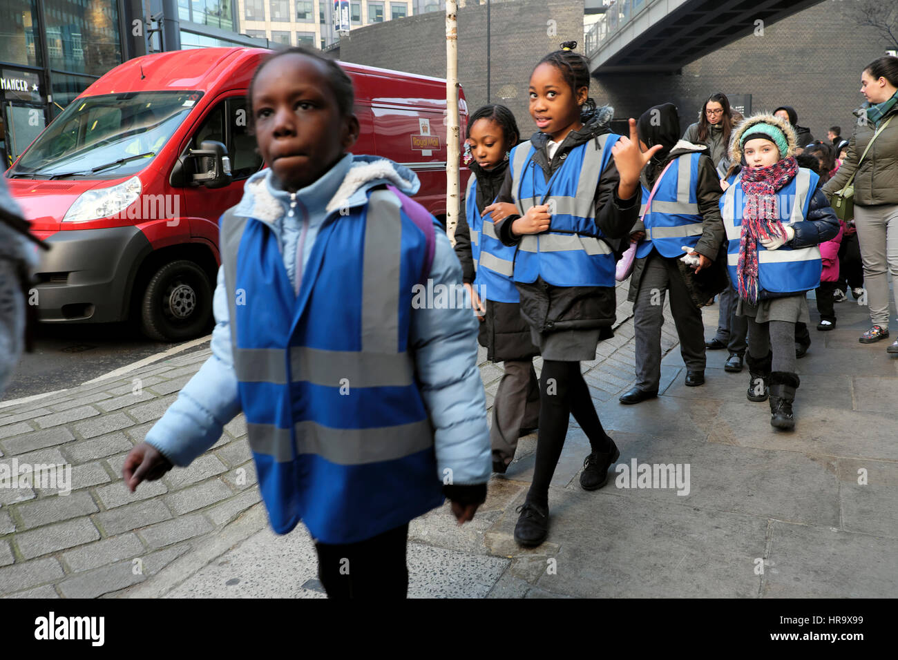 Bambini della scuola britannica all'aperto gruppo che indossa giubbotti blu a piedi lungo una strada dopo una visita al Museo di Londra Inghilterra KATHY DEWITT Regno Unito Foto Stock