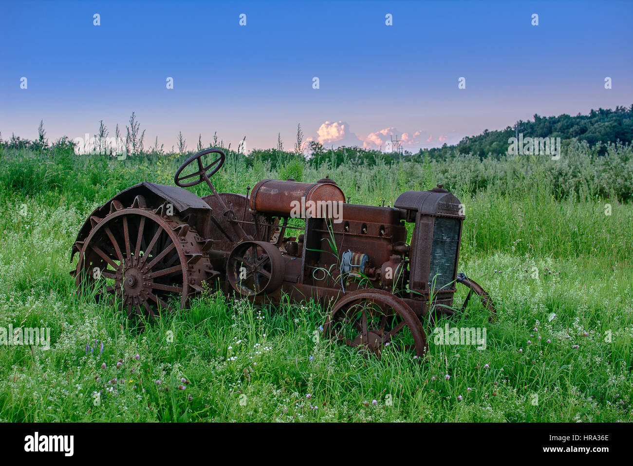 Un vecchio arrugginitoCormick-Deering Mc il trattore si trova in un campo incolto. Foto Stock