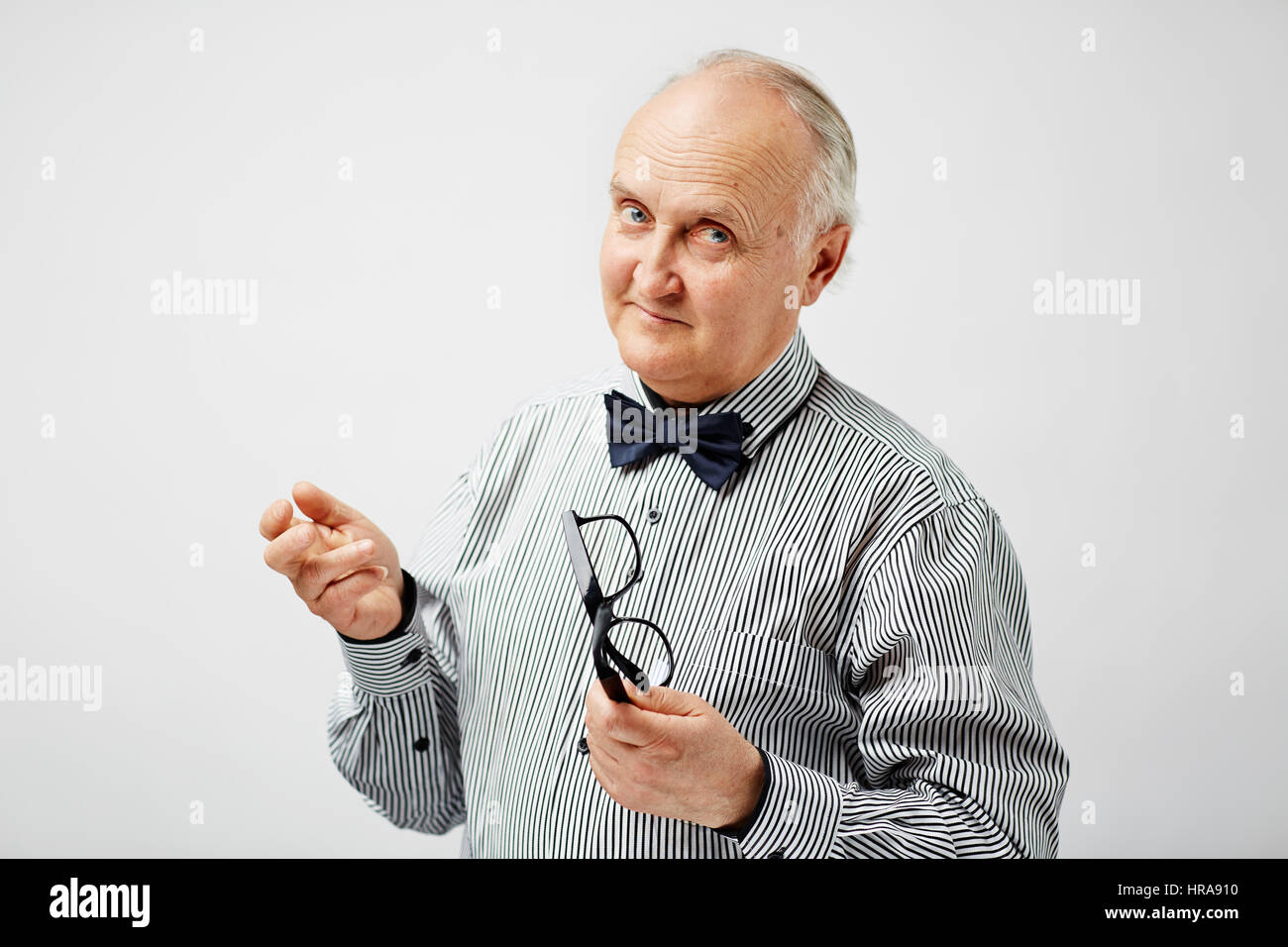 Ritratto di fiducia senior calvo Uomo in camicia a righe con il filtro bow  tie holding occhiali, guardando la fotocamera con quizzical sorriso Foto  stock - Alamy