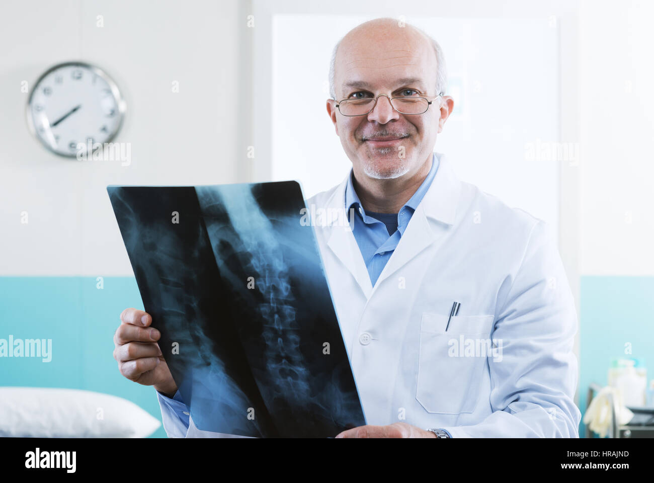 Senior maschili medico guardando immagini a raggi x della colonna vertebrale umana. Foto Stock