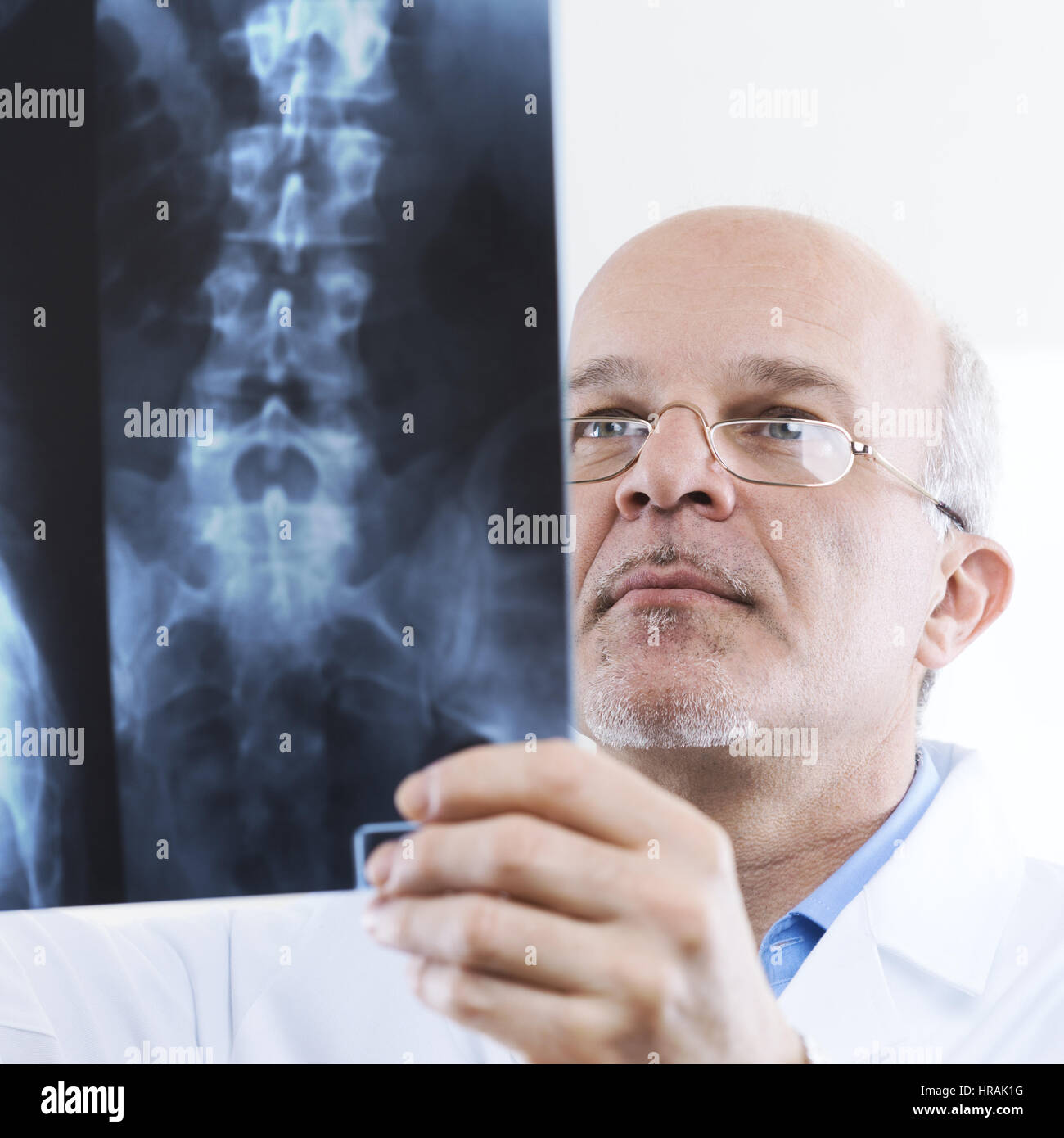 Senior maschili medico guardando immagini a raggi x della colonna vertebrale umana. Foto Stock