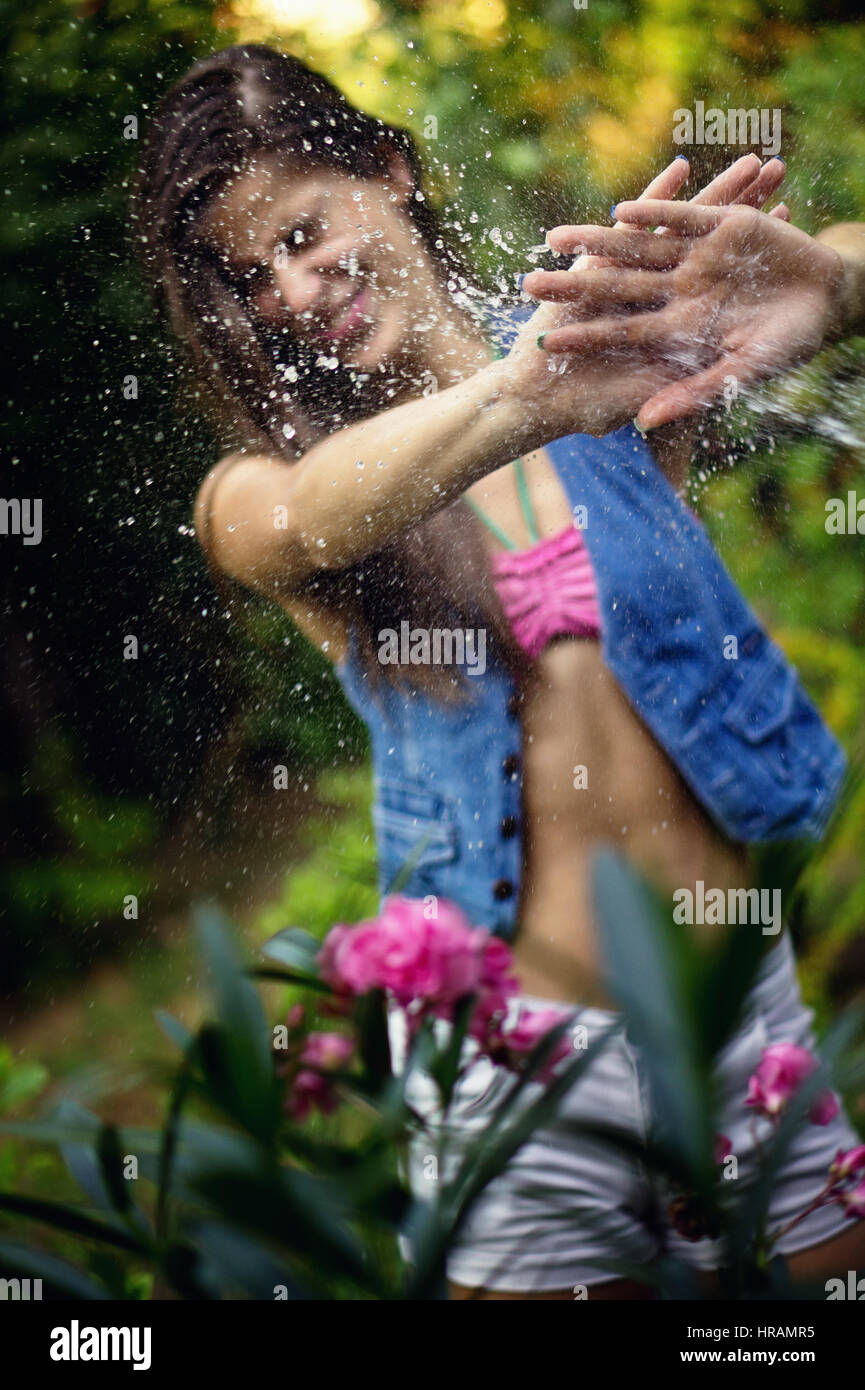 Bella giovane donna gioca con acqua in calore. La messa a fuoco è posto sul suo Palm. Bilanciamento del bianco personalizzato utilizzato e alcuni effetti di colore sono aggiunti a questo pi Foto Stock